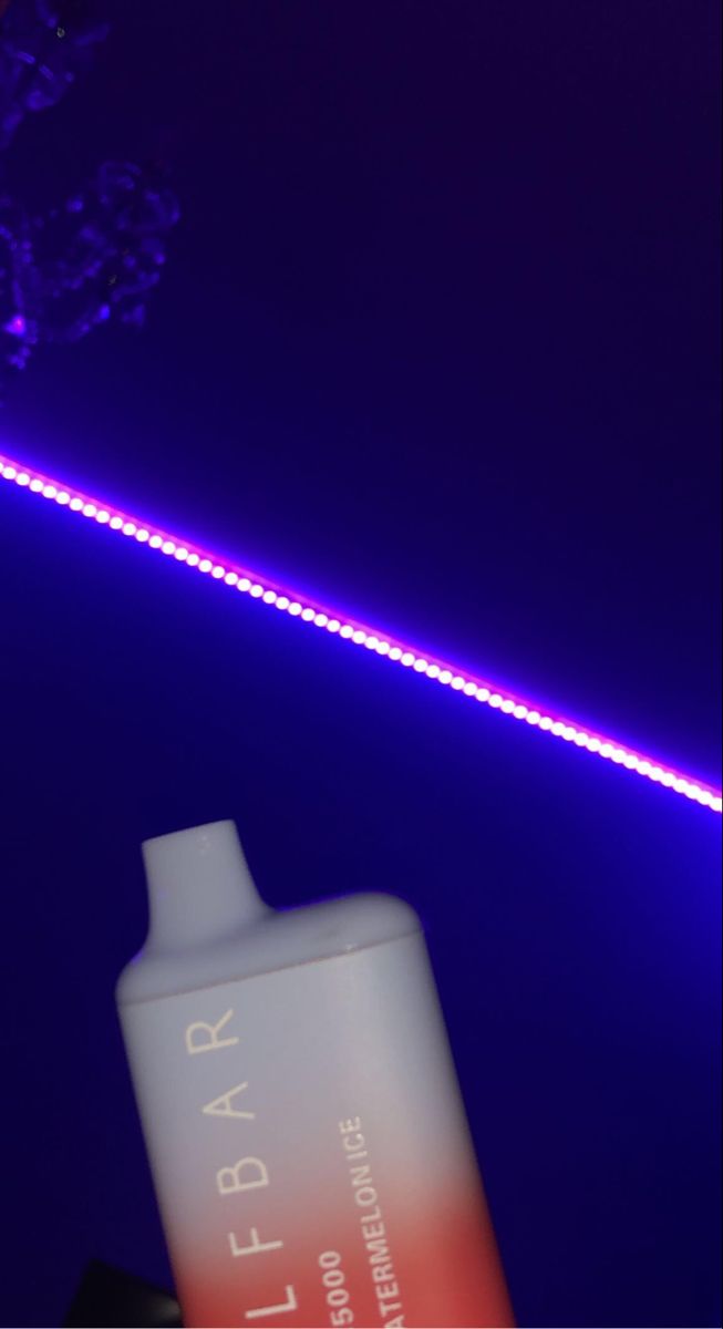 a purple and blue light shines in the background behind a tube of hair dye