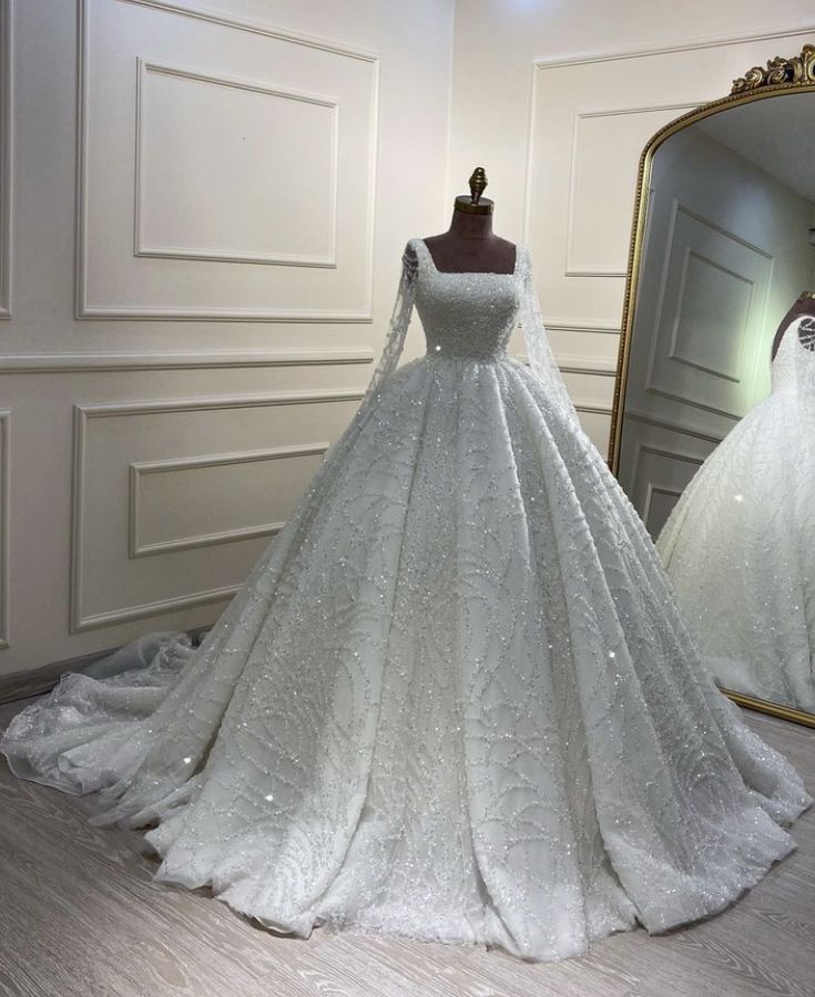 a white wedding dress on display in front of a mirror and mannequins