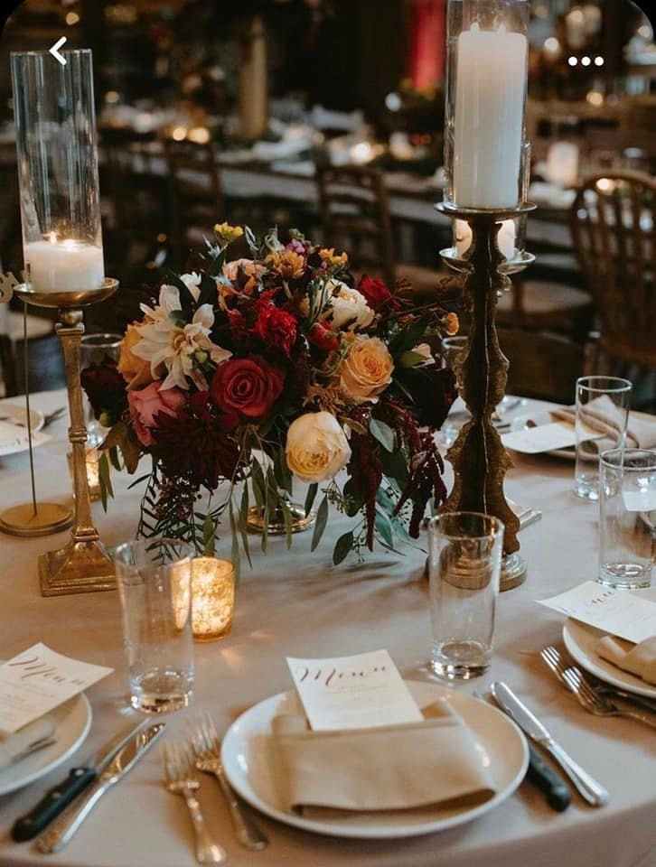 a table set with place settings, candles and flowers in vases on the tables