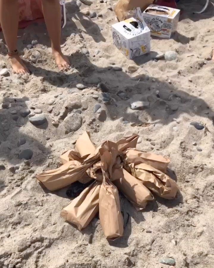 a bag is on the sand with people in the background and one person has their feet up