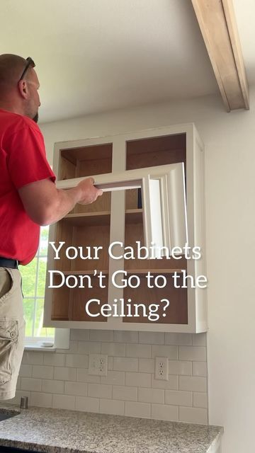 a man in red shirt and khaki pants standing next to cabinets with the words, your cabinets don't go to the ceiling?