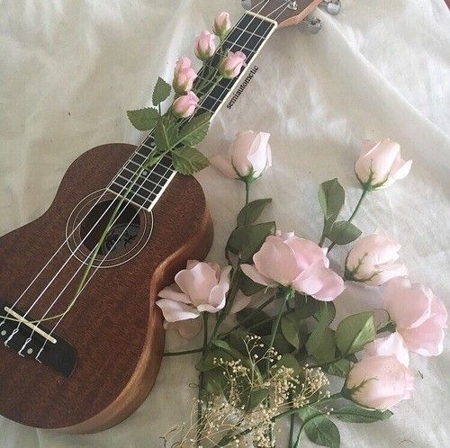 a ukulele and some flowers on a white sheet