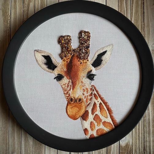 a close up of a giraffe's face in a frame on a wooden surface