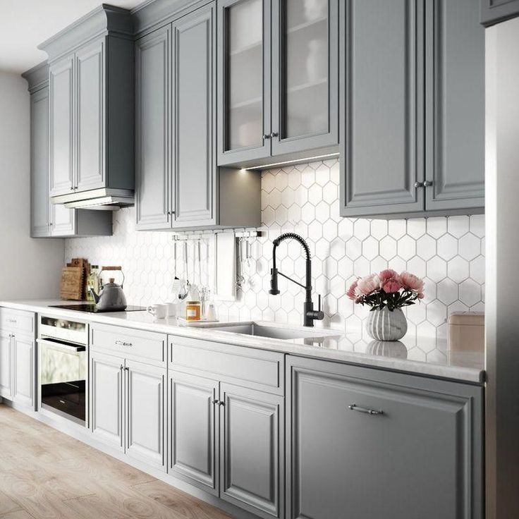 a kitchen with gray cabinets and white counter tops