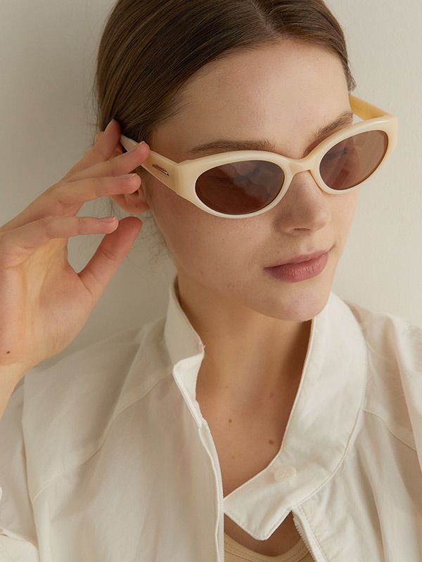 a woman in white shirt and sunglasses holding up her glasses