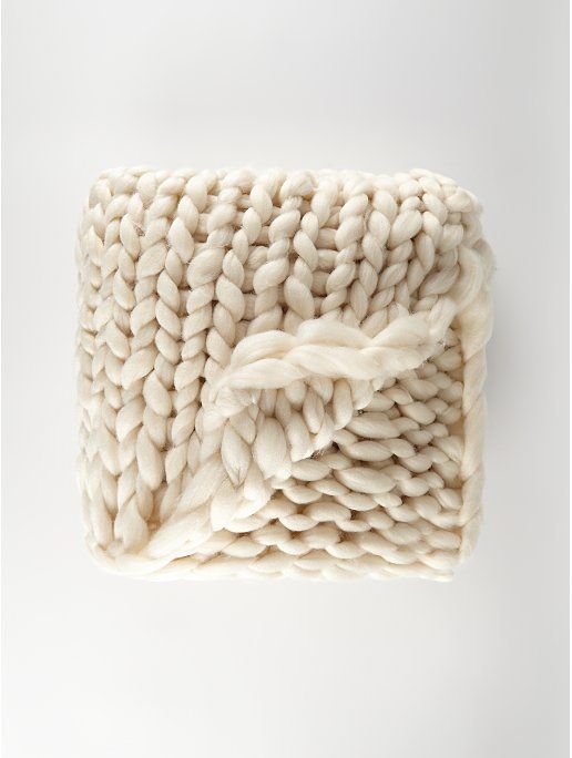 a white knitted blanket laying on top of a table