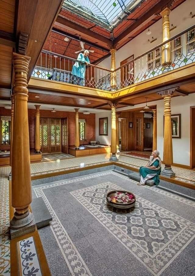 a person sitting on the floor in a large room with columns and an open balcony