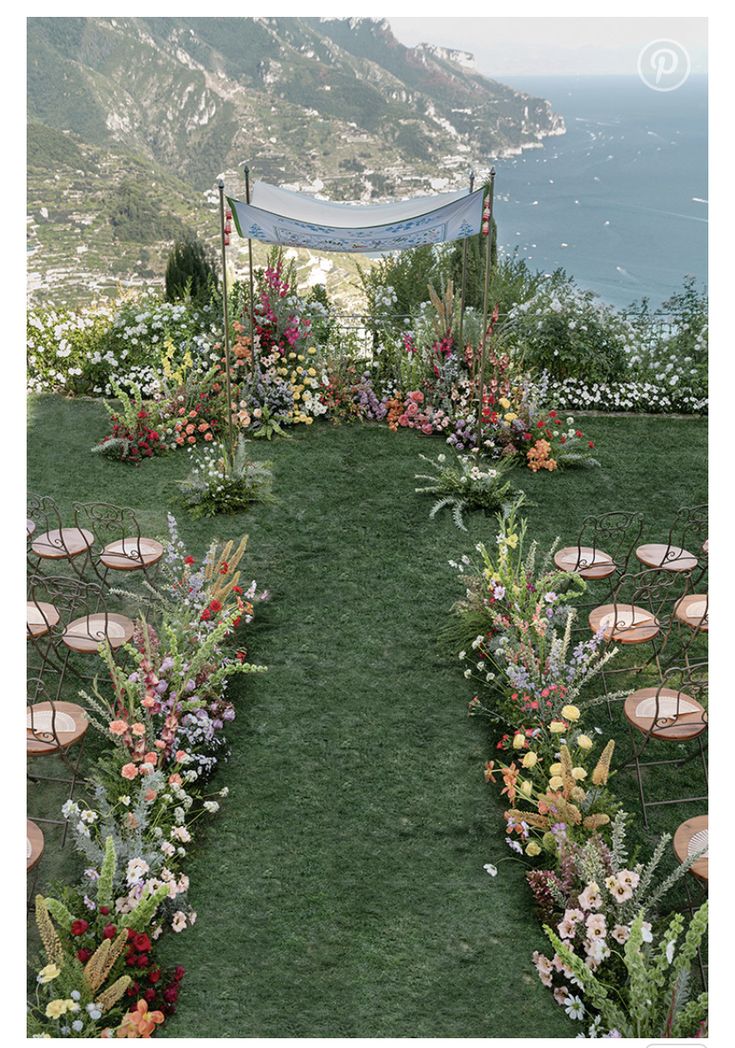 an outdoor ceremony setup with flowers and candles on the grass, overlooking the water's edge