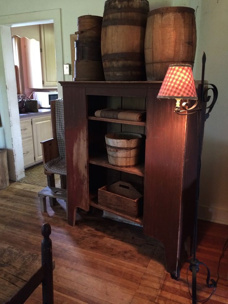 an old wooden cabinet with wine barrels on top and a lamp in the corner next to it