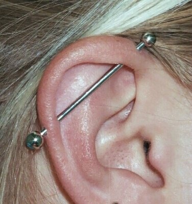 a woman's ear has three piercings on it