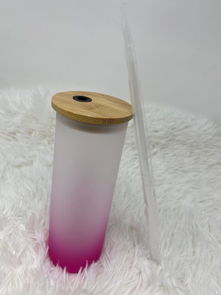 a pink and white vase sitting on top of a white fur covered floor next to a wooden lid