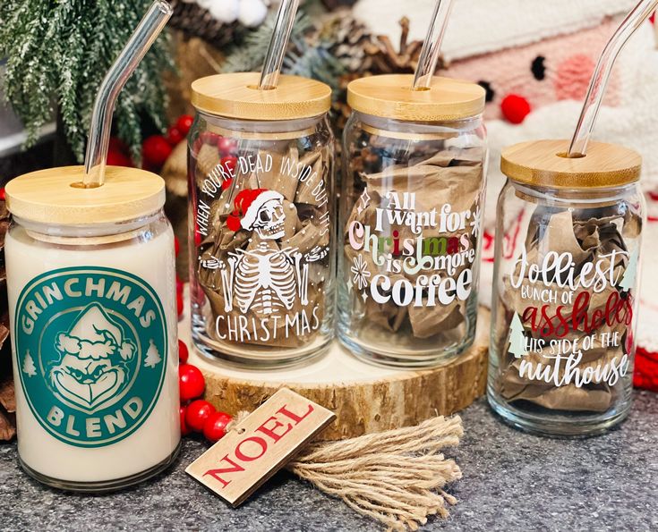 three glass jars with straws in them sitting on a table next to christmas decorations