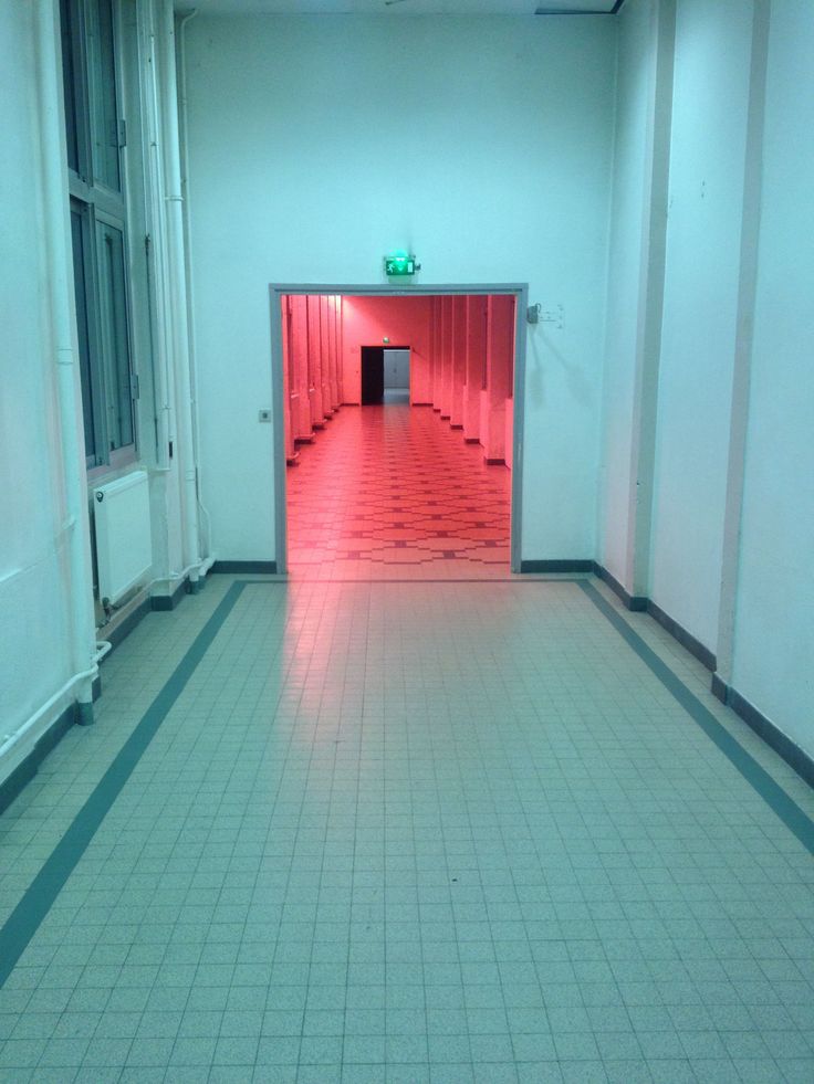 an empty hallway with red lights and tiled floors