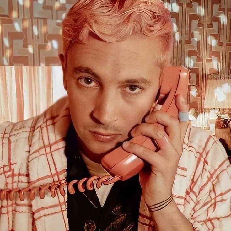 a man with pink hair is talking on the phone