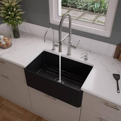 a black kitchen sink sitting under a window next to a white counter top with utensils on it