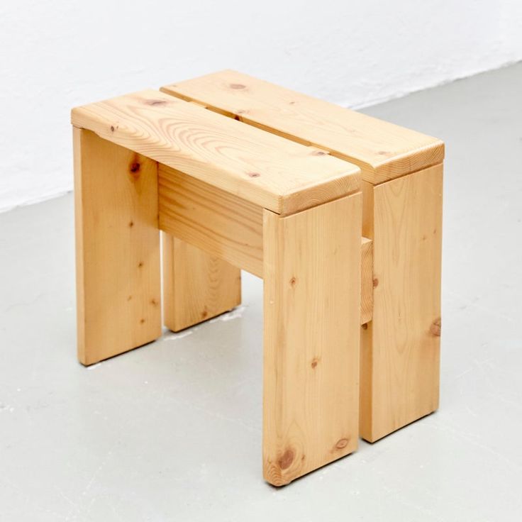 two wooden stools sitting side by side on the floor in front of a white wall