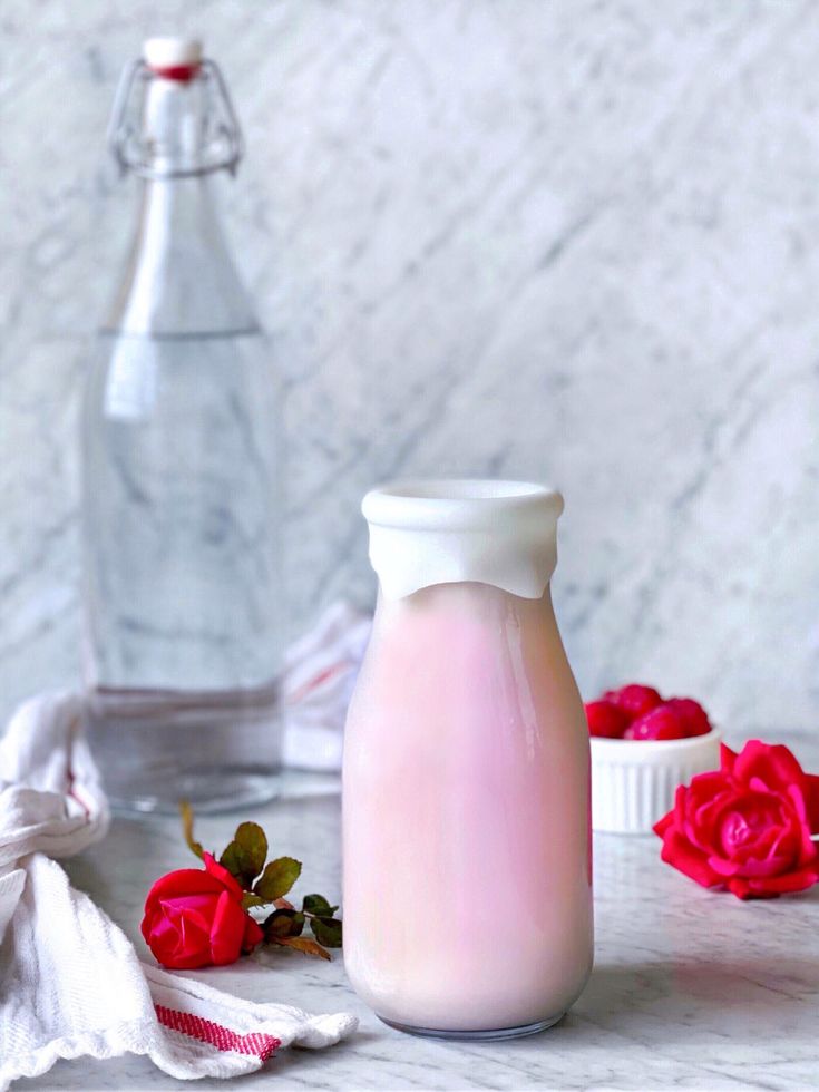 a bottle of milk and some roses on a table