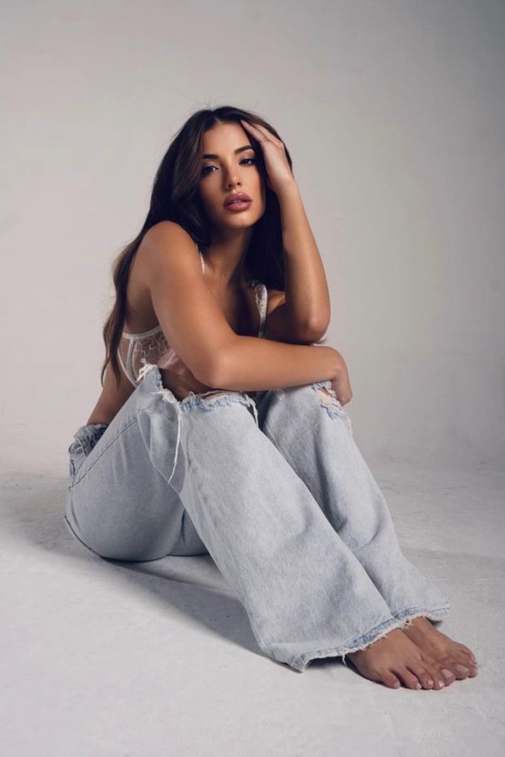 a woman is sitting on the floor with her legs crossed and looking at the camera