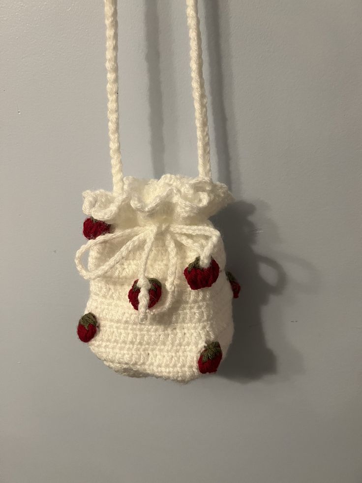 a crocheted bag hanging on the wall with strawberries attached to it's sides