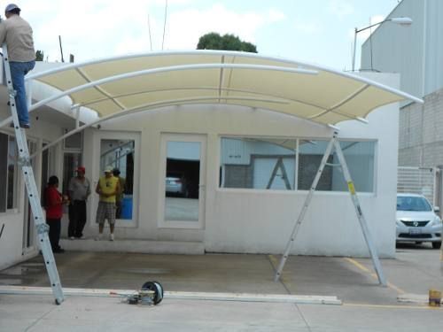 a man standing on top of a ladder next to an awning over a building