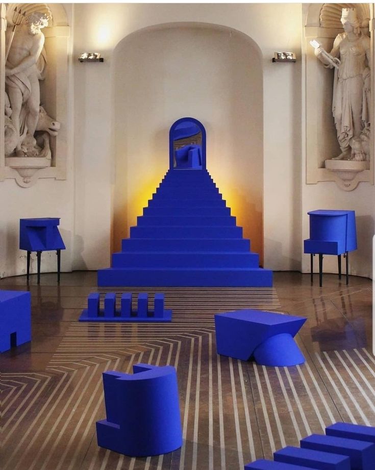 a room filled with lots of blue furniture next to two large statues and sculptures on the walls