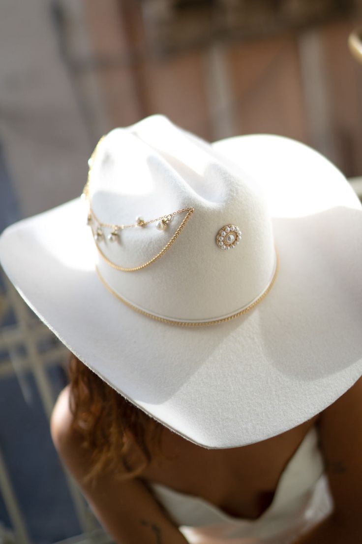 a woman wearing a white hat with pearls on the brim and chain around her neck