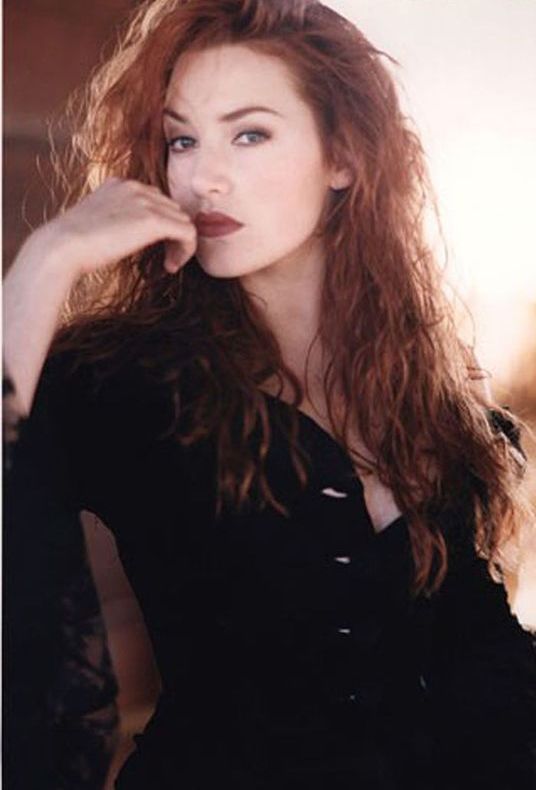 a woman with long red hair posing for the camera