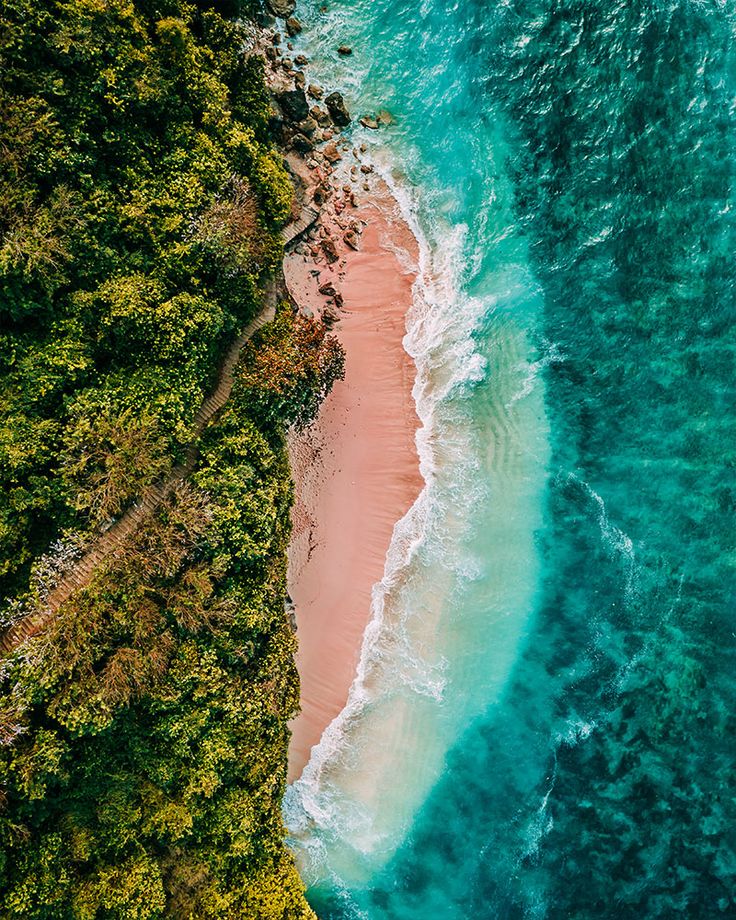 an aerial view of the ocean and beach with waves coming in from the shore, taken from above