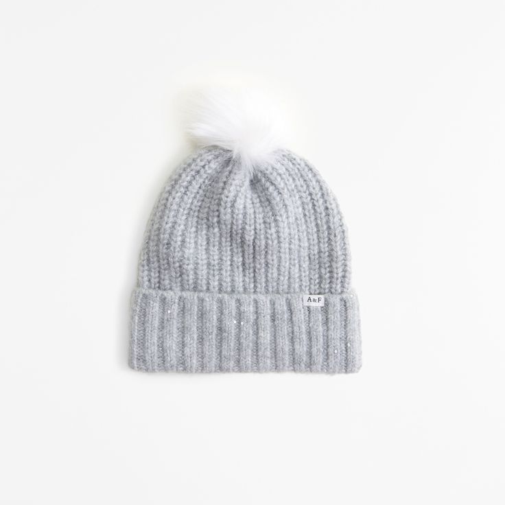 a grey hat with white pom - pom