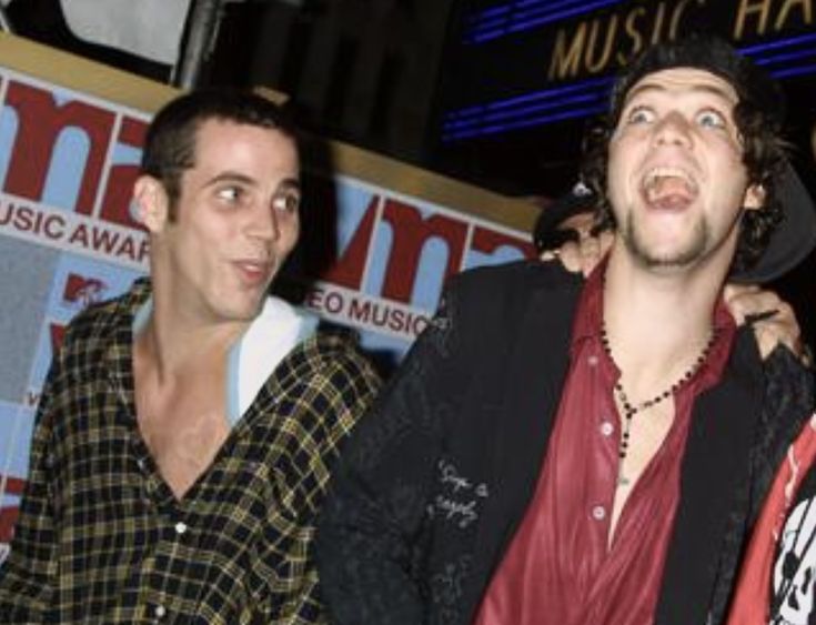 three men standing next to each other in front of a music hall sign at night