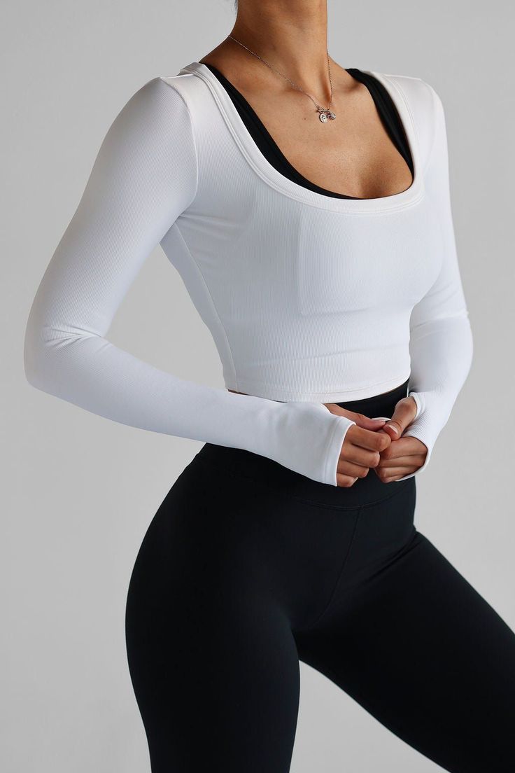 a woman in white shirt and black leggings with her hands on her hips