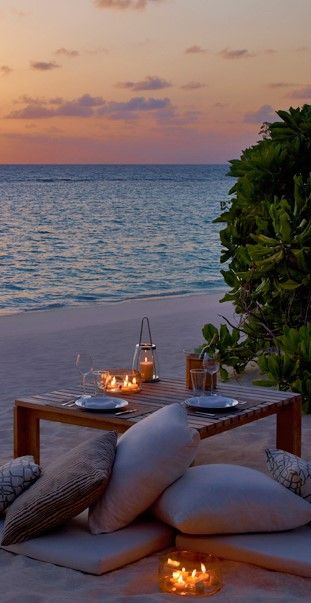 an outdoor dining area with candles on the beach