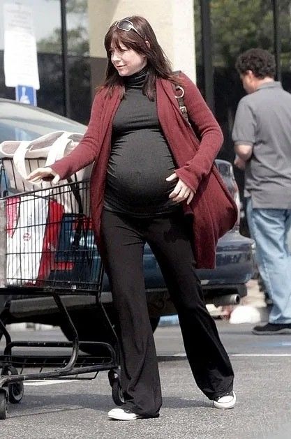 a pregnant woman pushing a shopping cart with her baby bump in it's belly