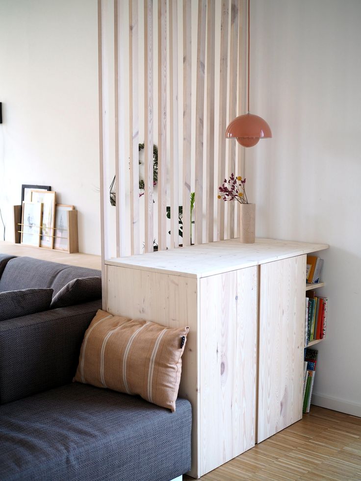 a living room with a couch, bookshelf and lamp on the side wall