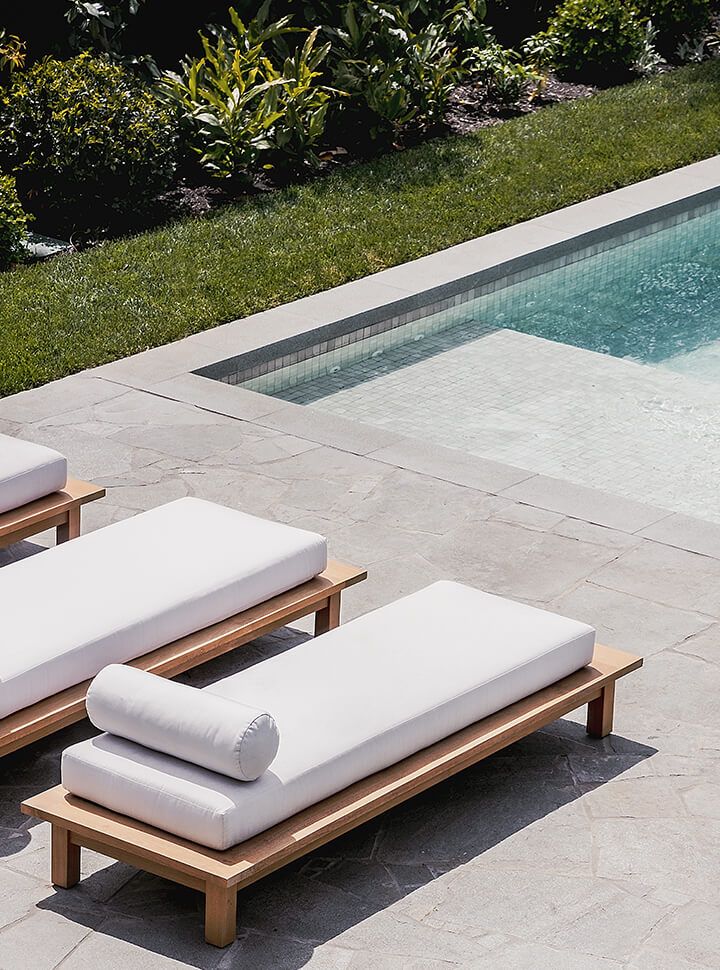 two lounge chairs next to a swimming pool