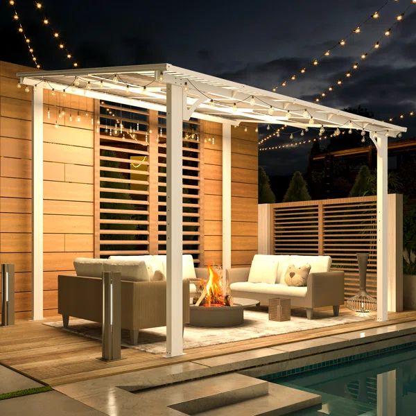 an outdoor living area next to a swimming pool at night with string lights on the roof