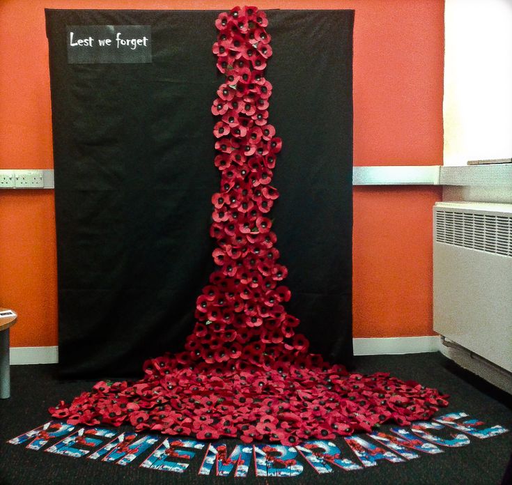 a room with an orange wall and red flowers on the floor next to a black curtain