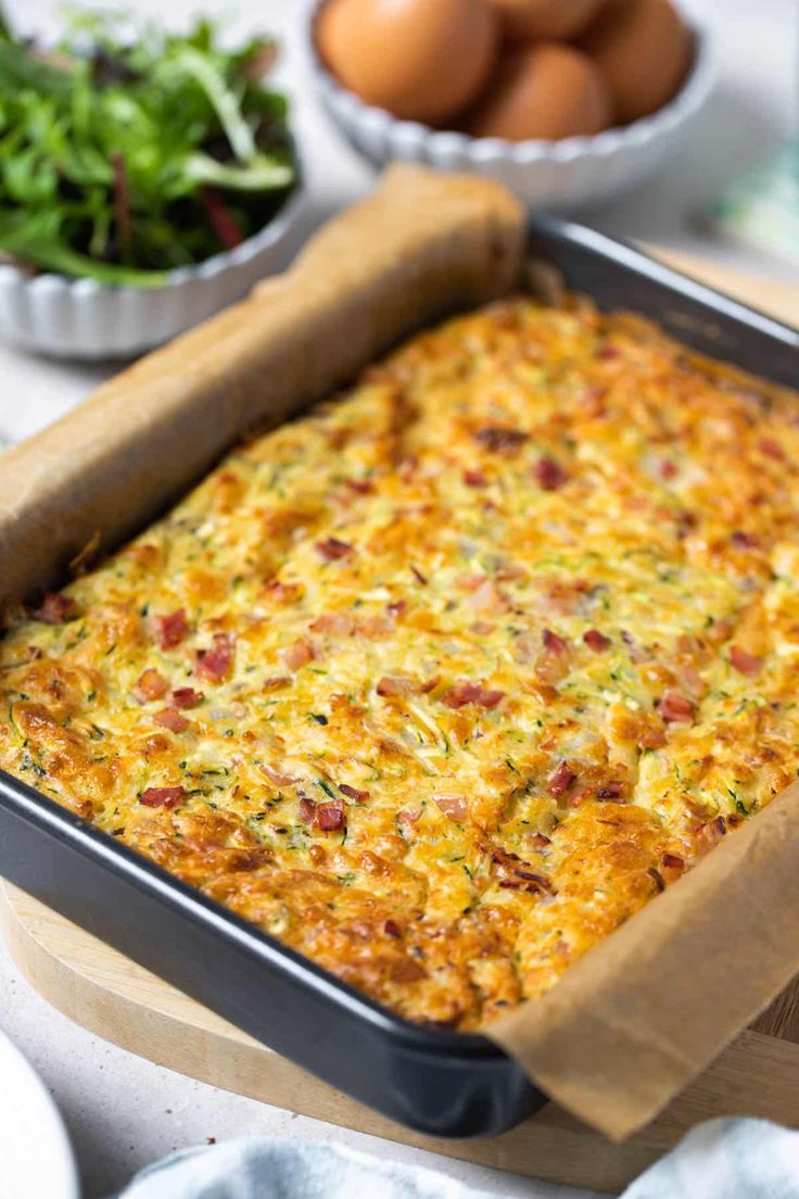 a casserole in a baking pan on a table with eggs and other ingredients