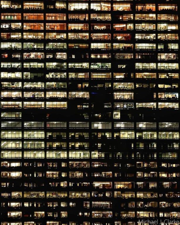 many windows are lit up at night in the building's dark colors and patterns