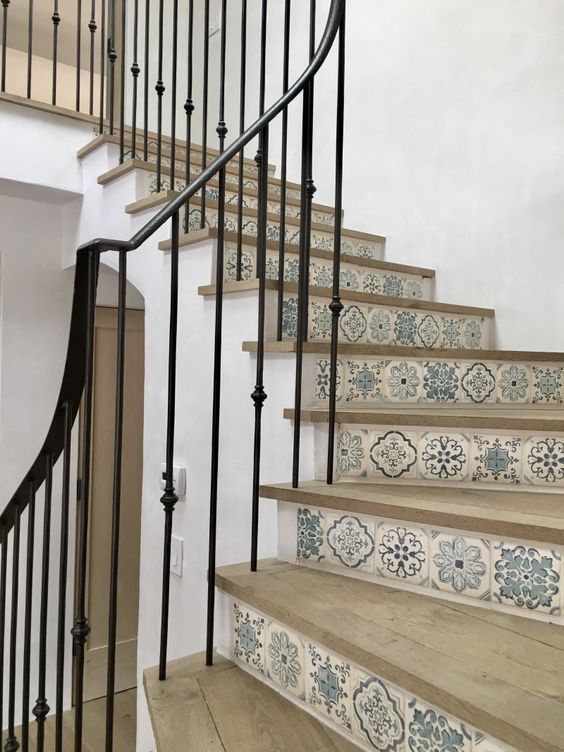 a stair case with blue and white tiles on the bottom, next to a wooden handrail