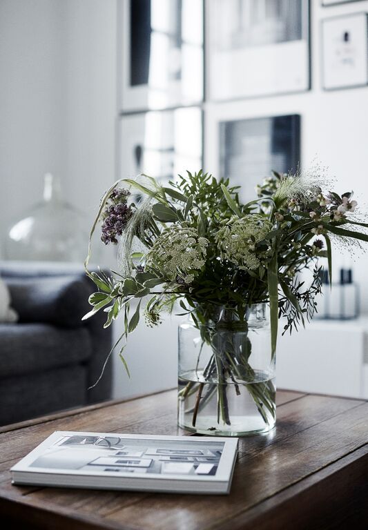 a vase filled with flowers sitting on top of a wooden table next to a couch