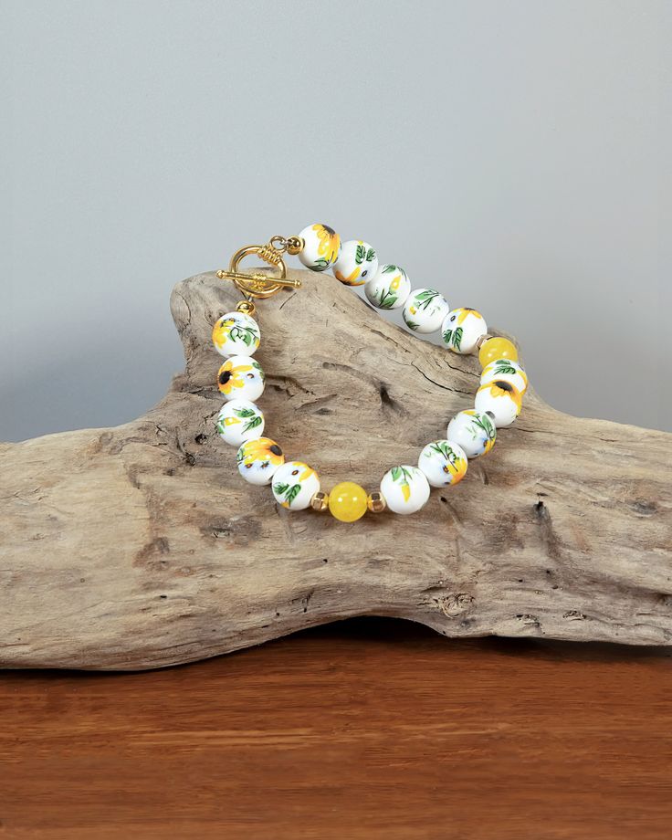 Beaded bracelet made of ceramic beads painted with sunflowers. It also has yellow jade and gold beads. It has a toggle clasp and is a size medium - 7.5 inches long. Yellow Beaded Bracelets, Yellow Combination, Sunflower Bracelet, Yellow Jade, Jade Beads, Ceramic Beads, Toggle Clasp, Gold Beads, Columbus