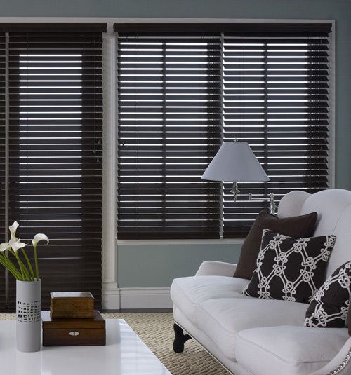 a living room with two couches and a table in front of the window that has blinds on it