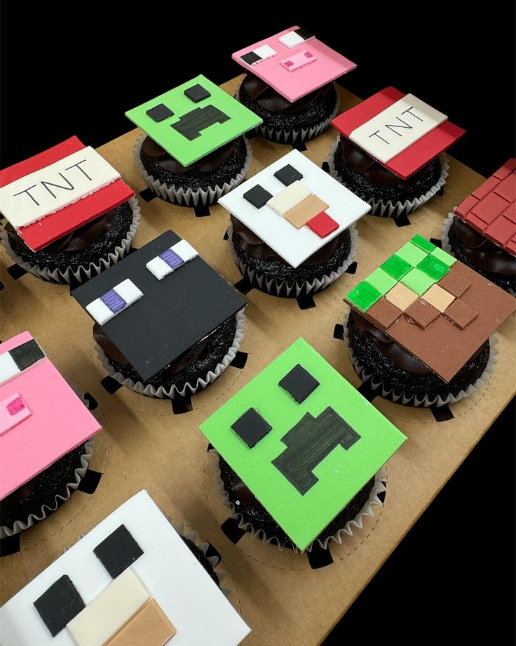 cupcakes made to look like minecraft houses are displayed on a table top