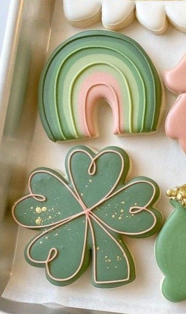 decorated cookies in the shape of shamrocks and rainbows are on a tray next to each other