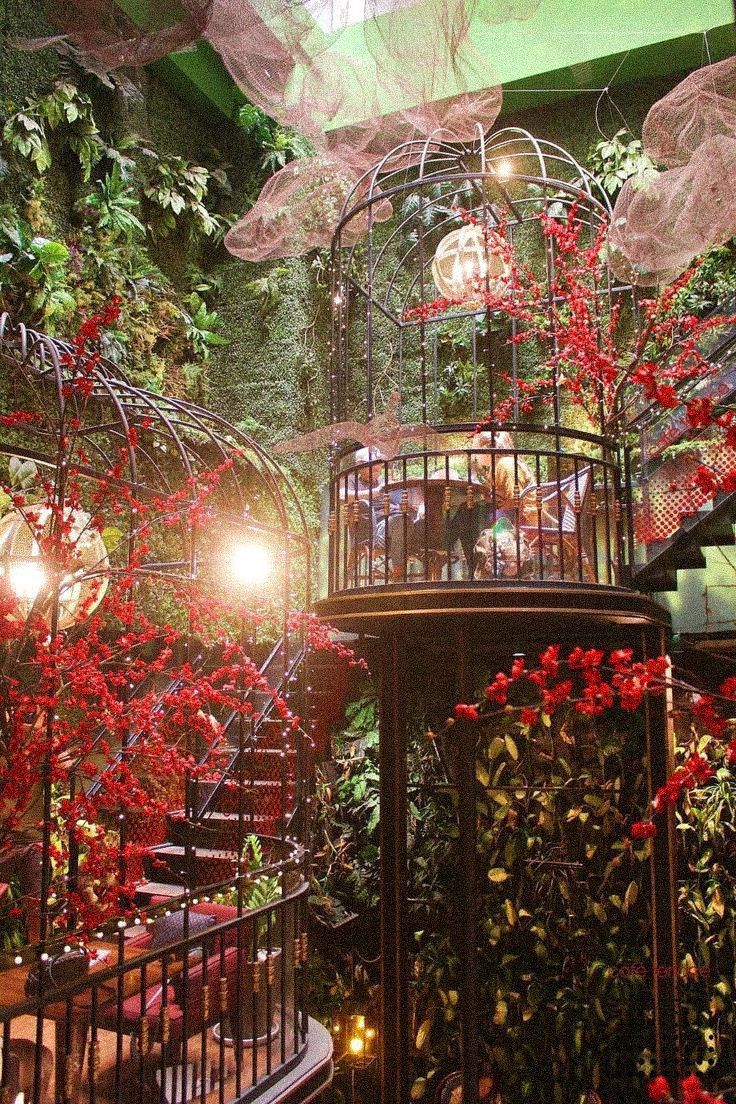 a birdcage filled with red flowers and greenery