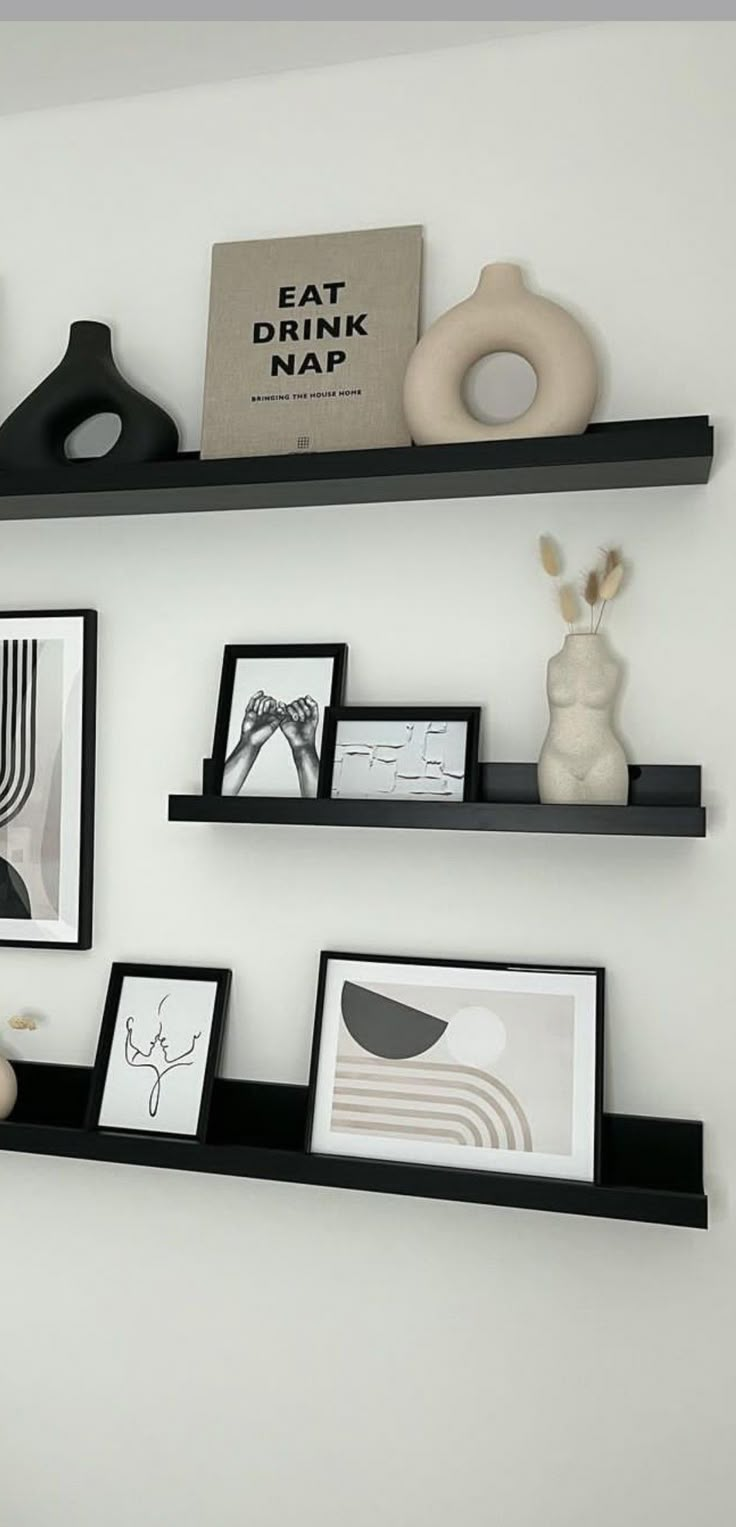 three black shelves with pictures and other items on them in a white walled wall area