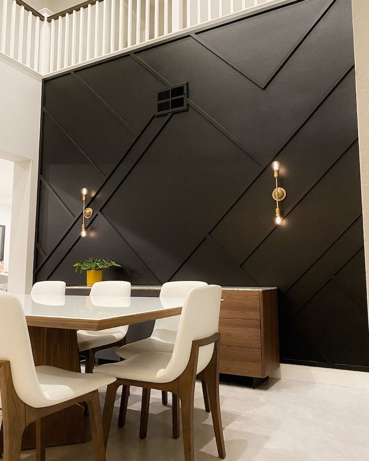 a dining room table with white chairs next to a black wall and wooden paneling