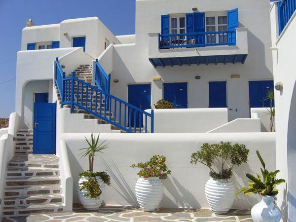 white buildings with blue doors and steps leading up to the front door are decorated with potted plants