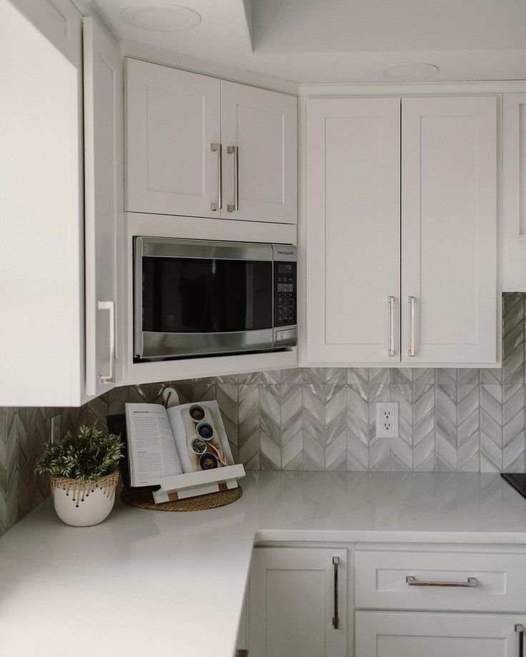 a kitchen with white cabinets and an open book on the counter next to the microwave